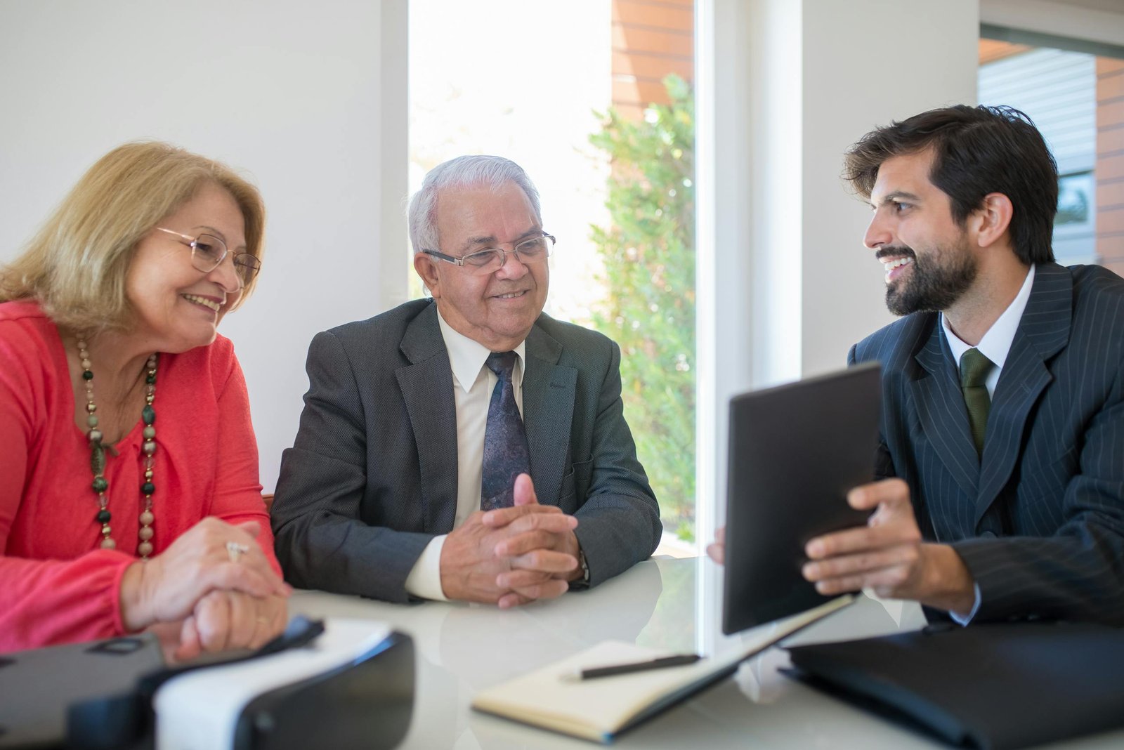 Elderly couple discussing real estate options with an agent in a modern office setting.